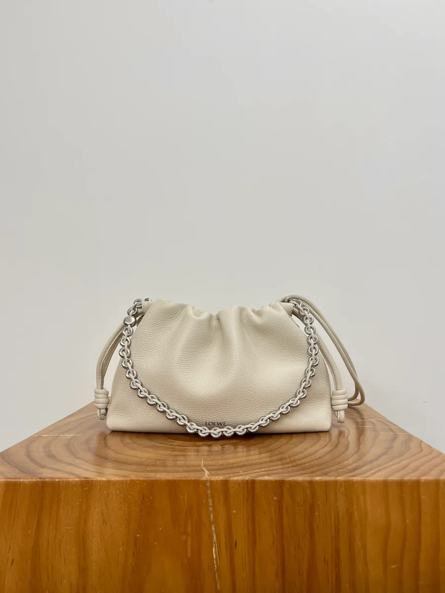 Белая кожаная сумка Loewe Flamenco с цепочкой на деревянной подставке, вид спереди.