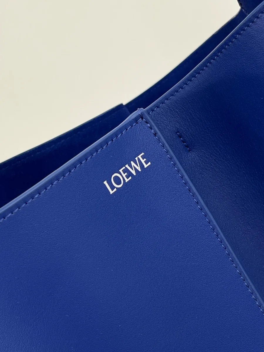 Крупный план верхнего края синей сумки с серебристым логотипом Loewe