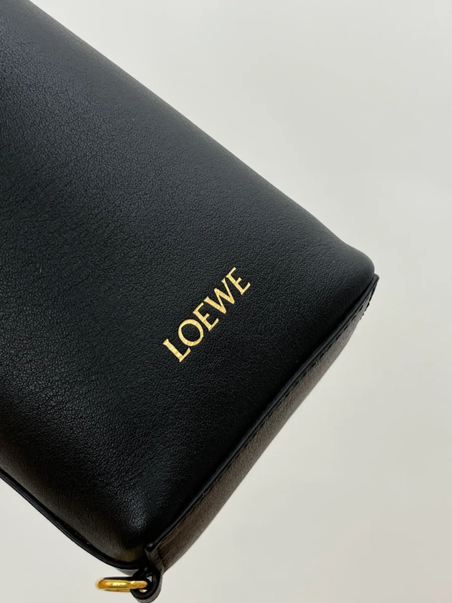 Крупный план золотистого тиснения с логотипом LOEWE на гладкой чёрной коже