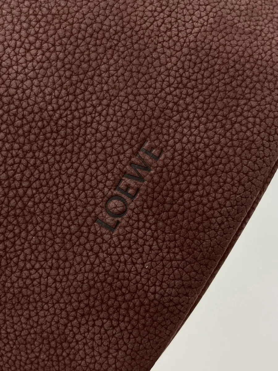Крупный план тиснения логотипа Loewe на тёмно-коричневой зернистой коже
