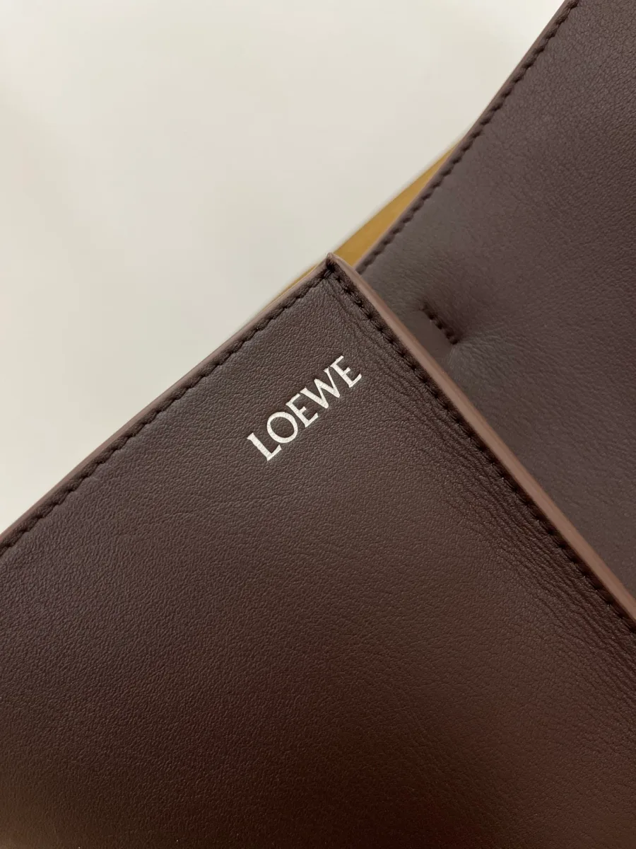 Крупный план серебристого тиснения логотипа Loewe на гладкой коричневой коже