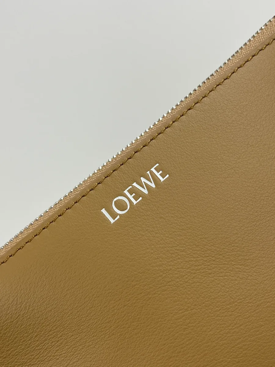 Крупный план серебристого тиснения логотипа Loewe на коже оттенка мокко
