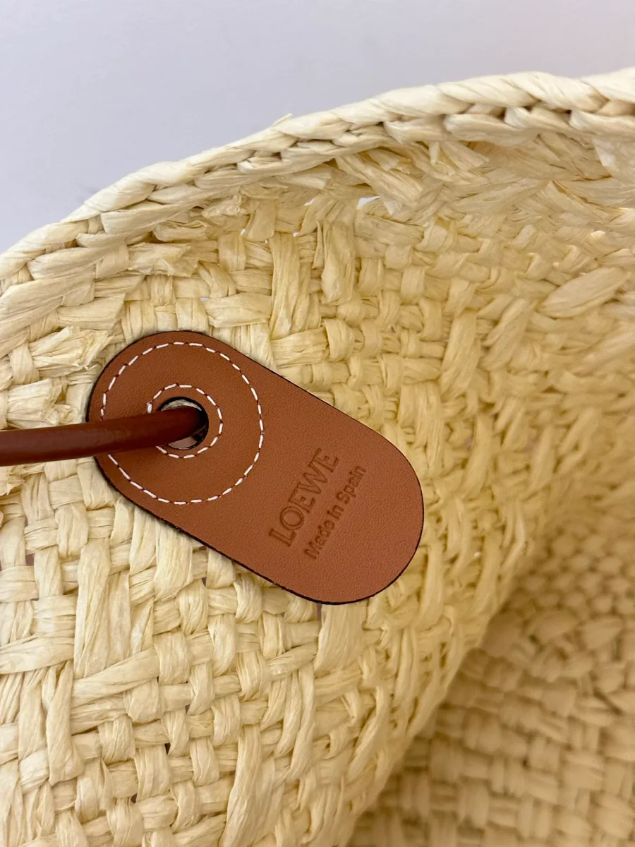 Внутренняя кожаная бирка с тиснением названия бренда LOEWE на фоне плетёной фактуры
