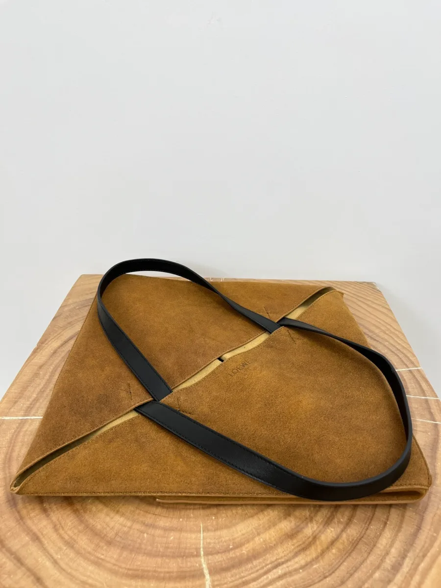 Сумка-тоут Loewe Puzzle Fold в полностью сложенном виде на деревянной поверхности