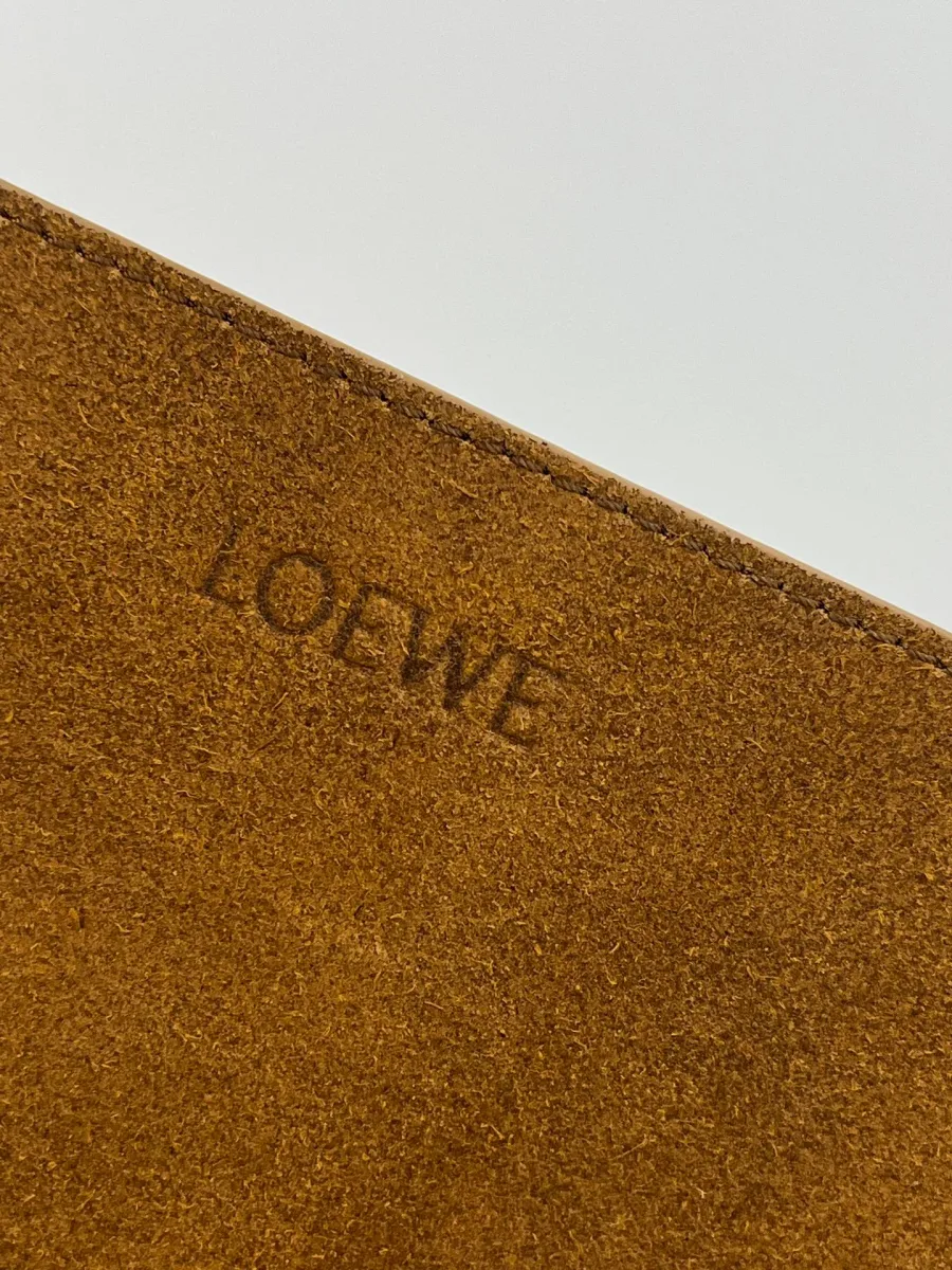Крупный план тиснения логотипа Loewe на фактурной коричневой замше
