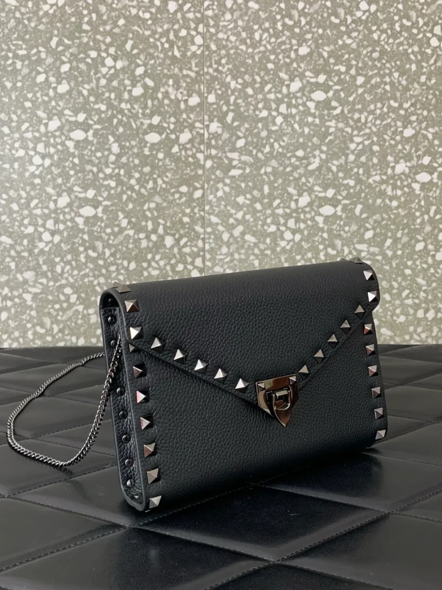 Чёрная сумка Valentino Rockstud с цепочкой и отделкой металлическими шипами, ракурс три четверти