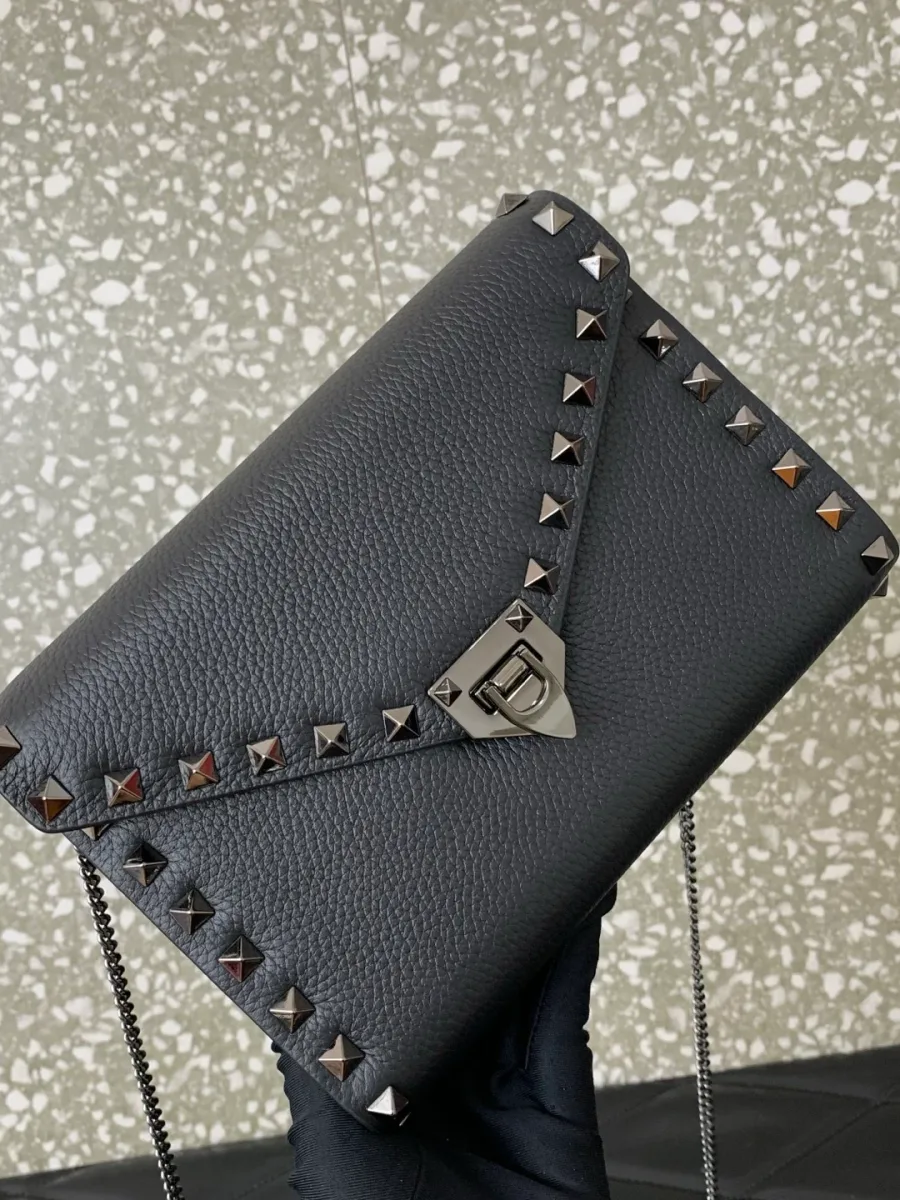 Чёрная сумка Valentino Rockstud в руке, вид на компактный корпус и фактуру кожи