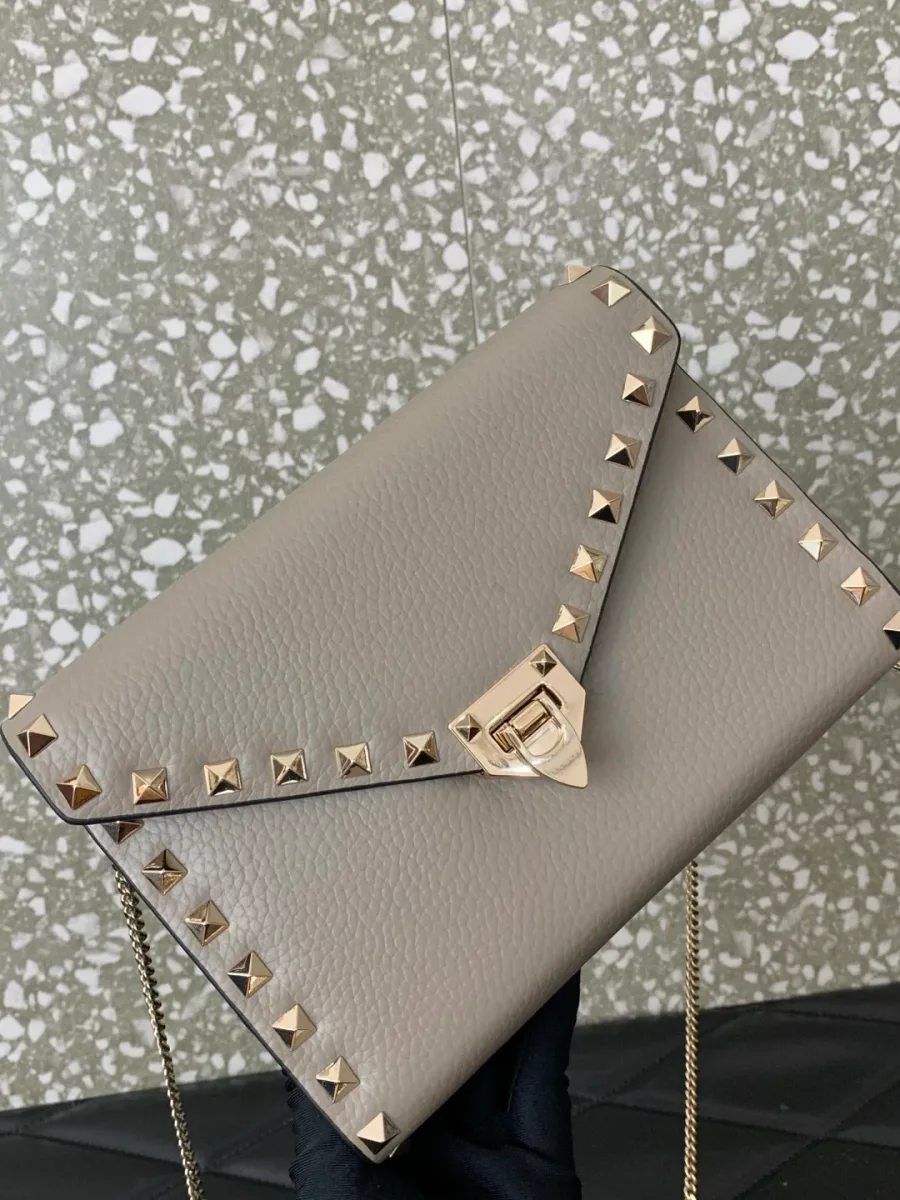 Бежевая сумка Rockstud в руке, вид на клапан и зернистую текстуру кожи