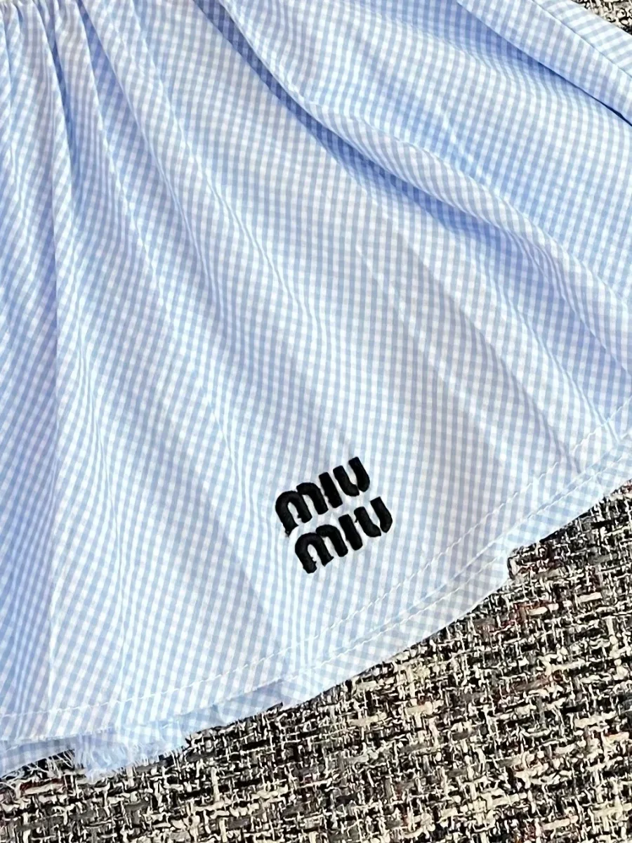 Вышитый черный логотип Miu Miu на подоле юбки в клетку виши