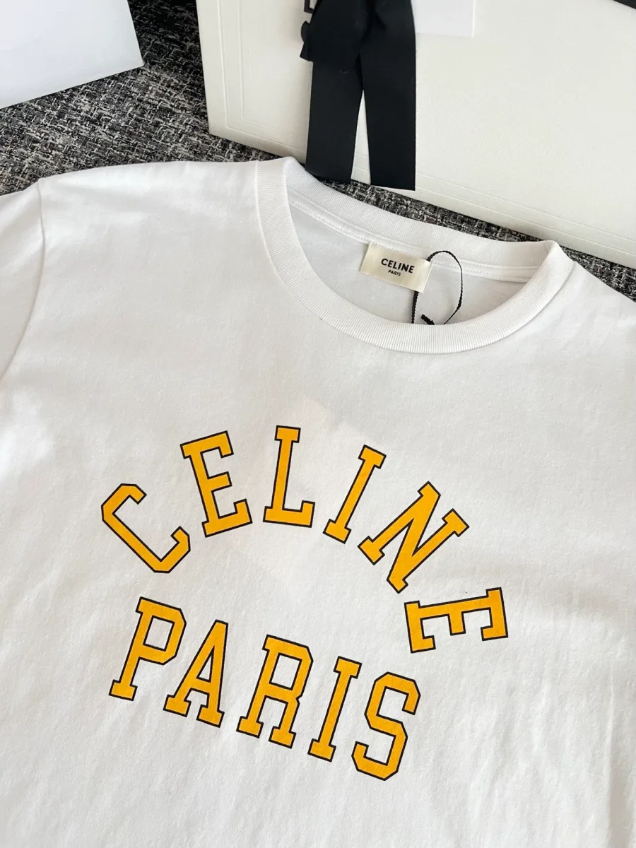 Крупный план жёлтого шрифтового принта Celine Paris на груди белой футболки