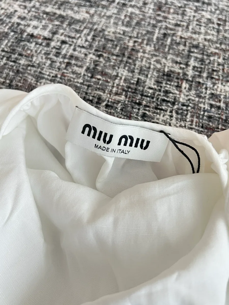 Текстильный ярлык с логотипом Miu Miu и указанием страны производства на горловине