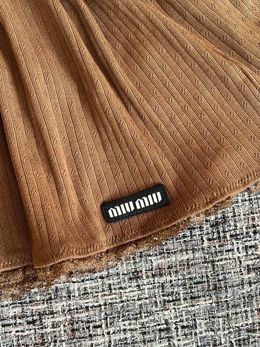 Текстильный патч с логотипом Miu Miu на нижнем крае коричневой юбки