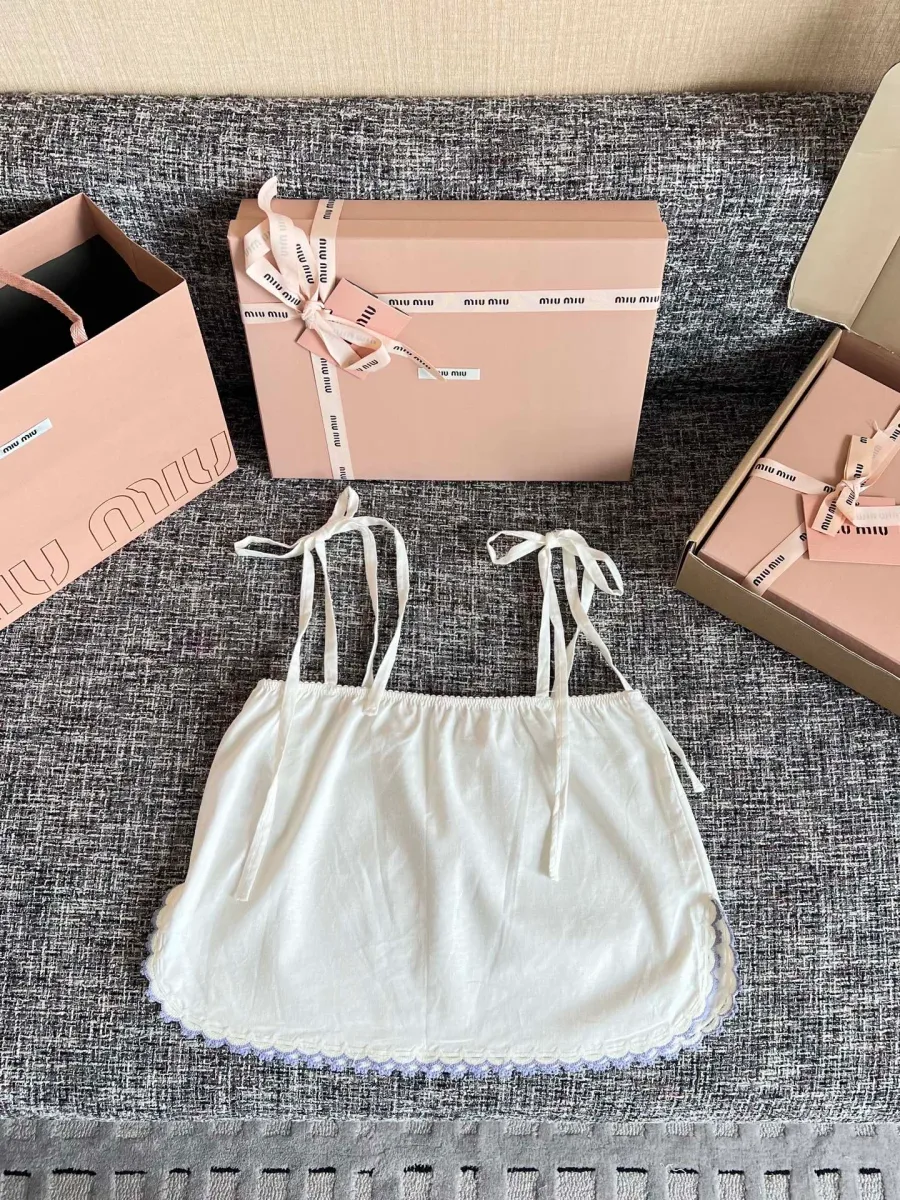 Белый укороченный топ на завязках на фоне коробок Miu Miu