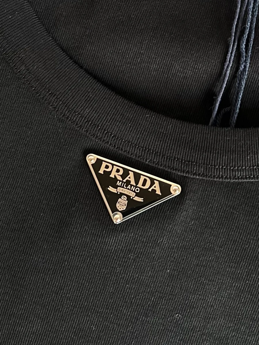 Крупный план эмалевой треугольной пластины с логотипом Prada на груди