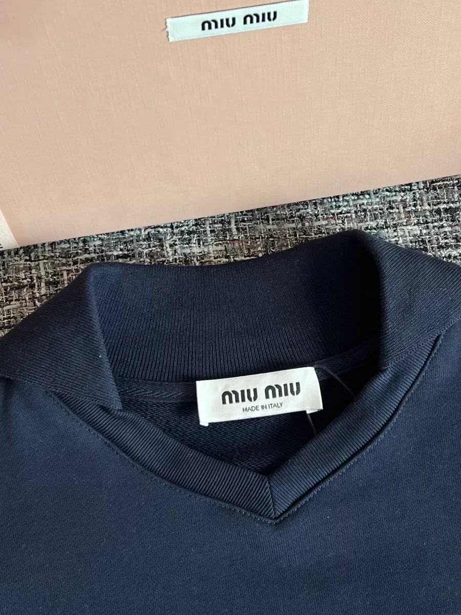 V-образный вырез горловины и текстильный ярлык Miu Miu крупным планом