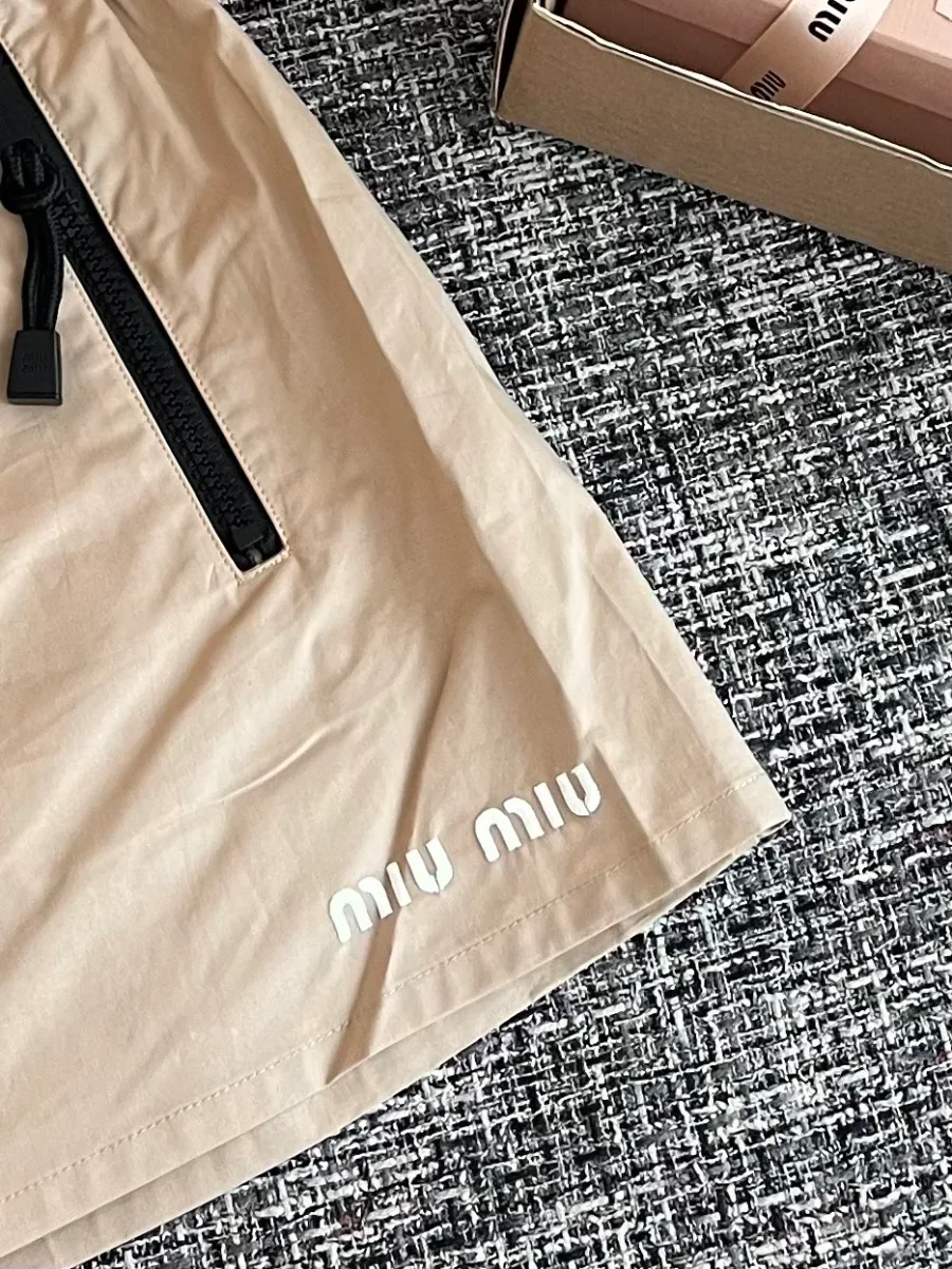 Белый вышитый логотип бренда в нижней части подола