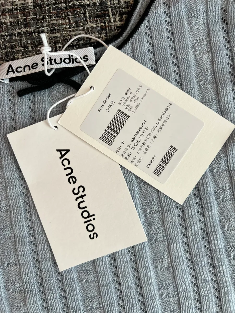 Фирменные навесные бирки Acne Studios на фоне серого трикотажа