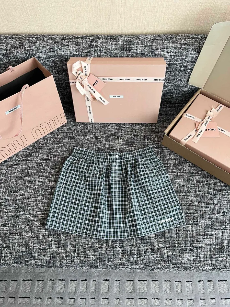 Зелёная юбка в клетку с коробками Miu Miu на сером фоне, общий вид