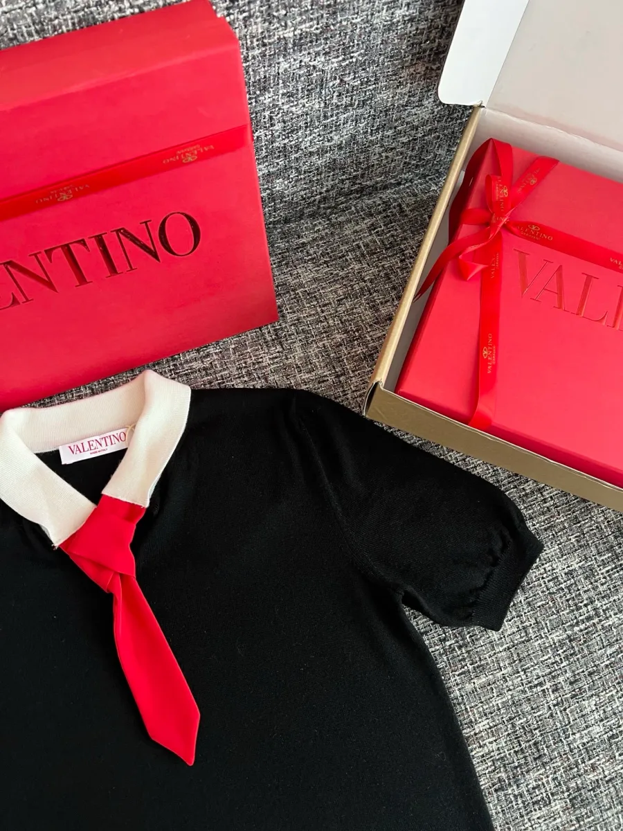 Рукав и воротник чёрной футболки Valentino рядом с подарочной упаковкой