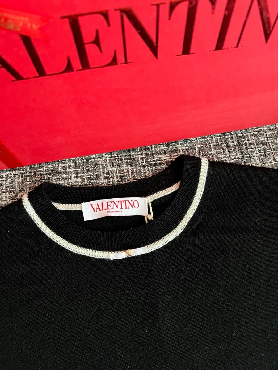 Круглый вырез горловины со светлым кантом и биркой Valentino крупным планом