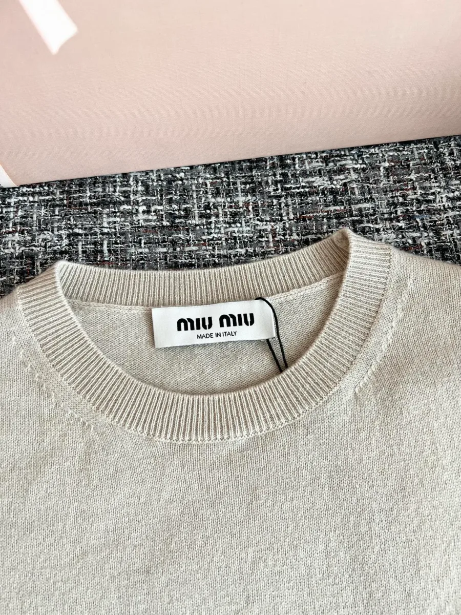 Круглый вырез горловины в рубчик с фирменной биркой Miu Miu крупным планом