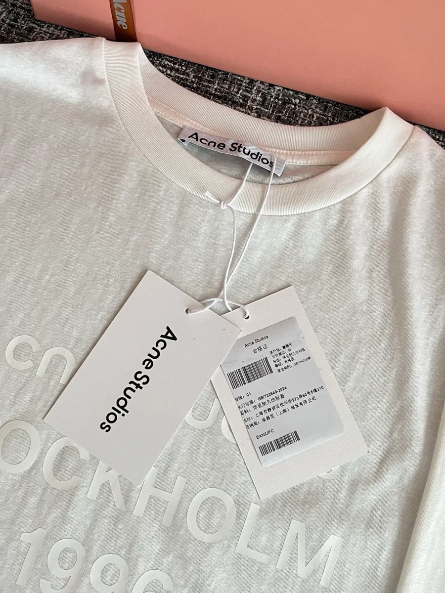 Фирменные бирки и горловина белого лонгслива Acne Studios
