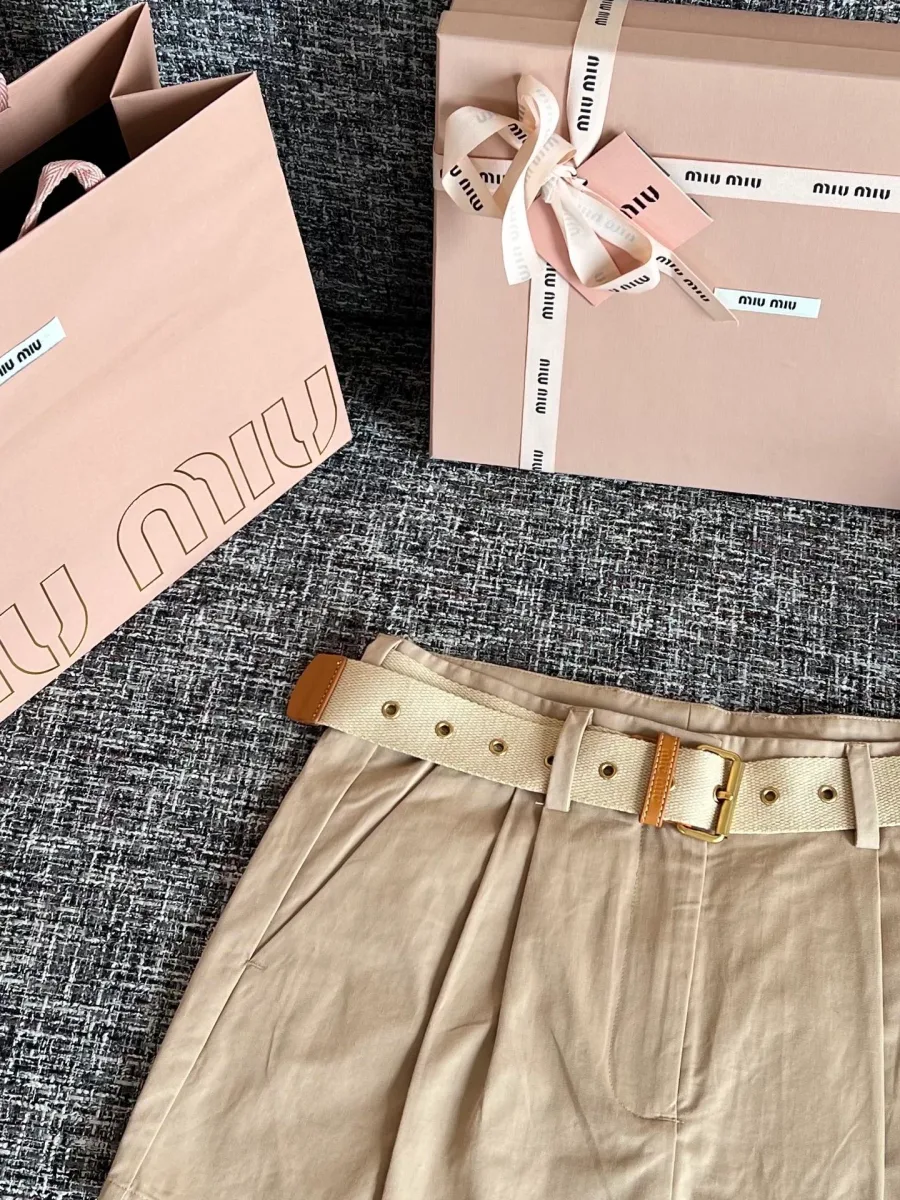 Пояс бежевой мини-юбки с ремнём, люверсами и защипами