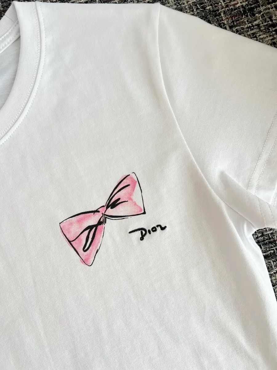 Крупный план принта на груди в виде розового банта с рукописной надписью Dior