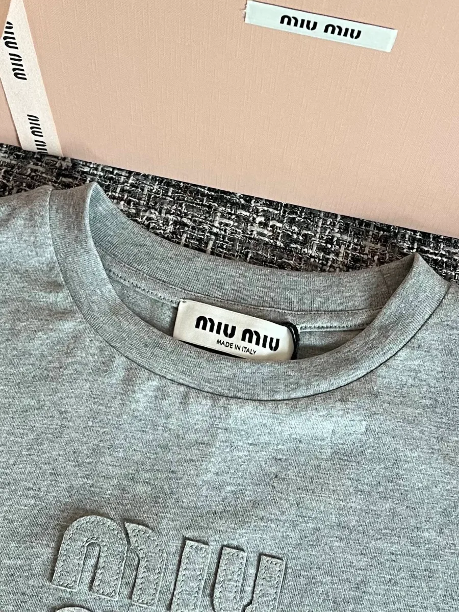 Круглый вырез горловины и фирменный ярлык Miu Miu на серой футболке