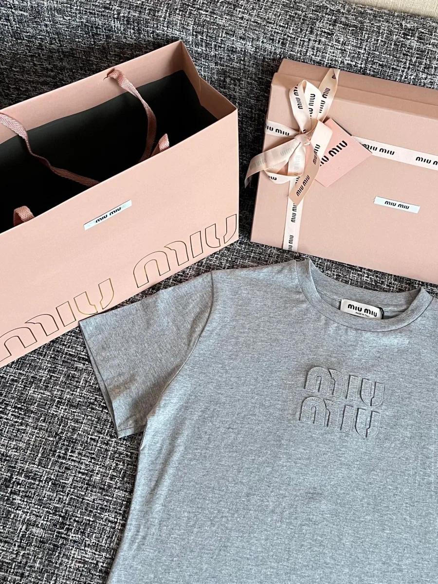 Серая футболка с объемным вышитым логотипом Miu Miu, ракурс под углом