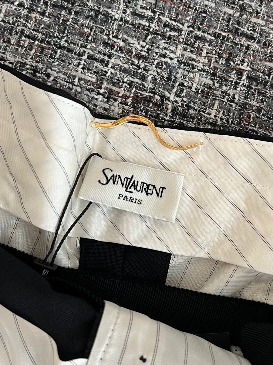 Внутренняя бирка с логотипом Saint Laurent Paris на фоне полосатой подкладки