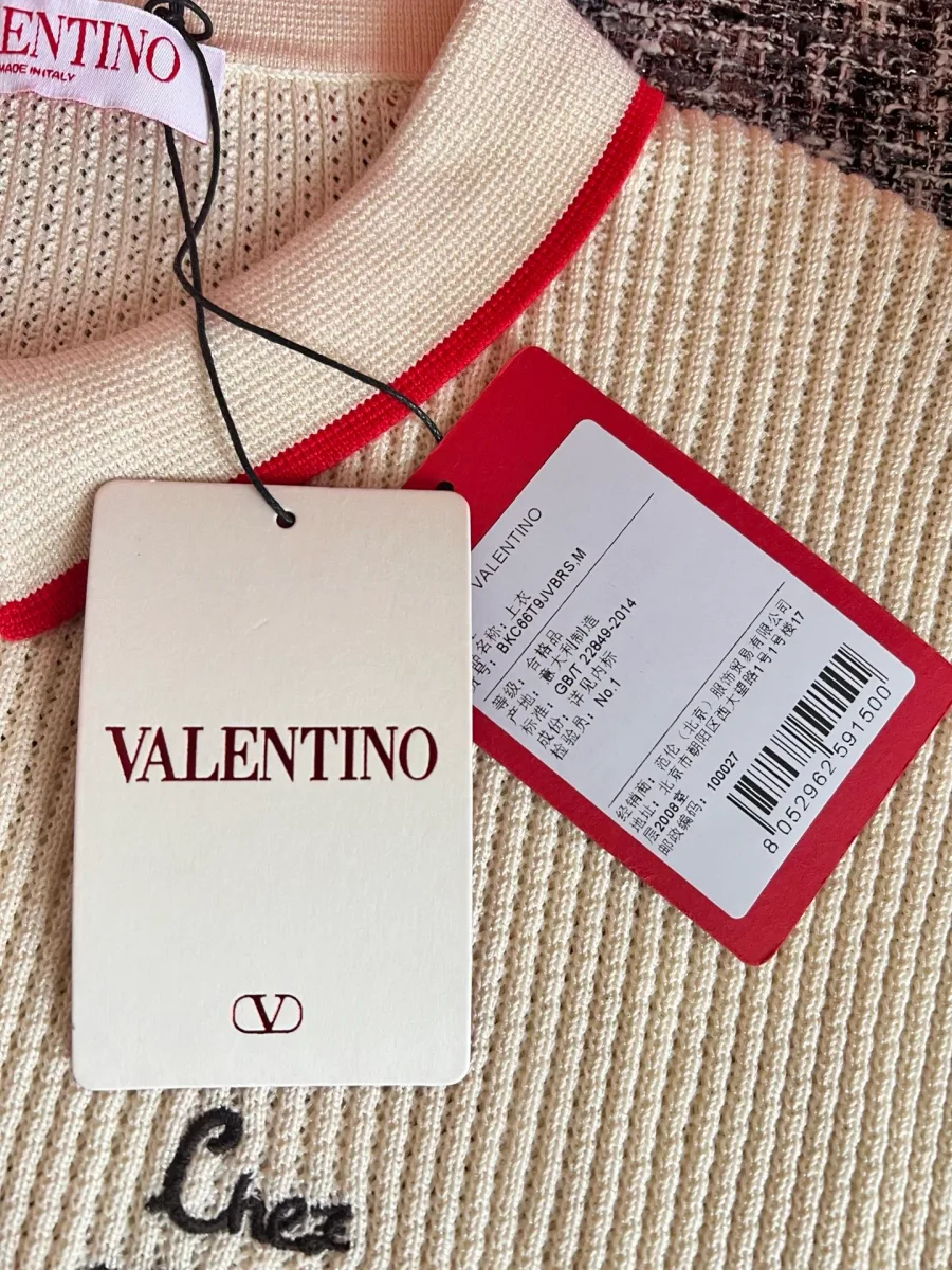 Фирменные навесные бирки Valentino на фоне фактурного полотна жилета