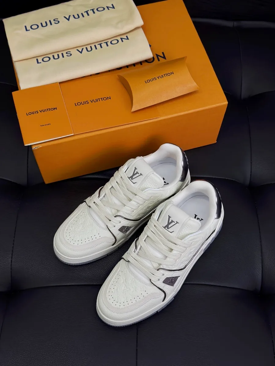 Белые кроссовки LV Trainer рядом с фирменной коробкой и пыльниками, ракурс сверху