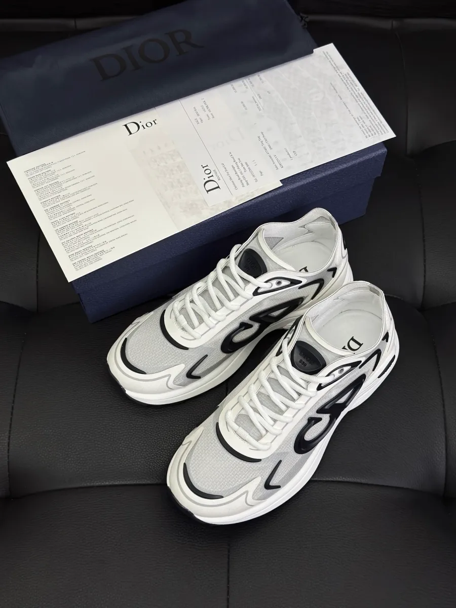 Белые кроссовки Dior B30 рядом с фирменной коробкой, вид сверху на темном фоне