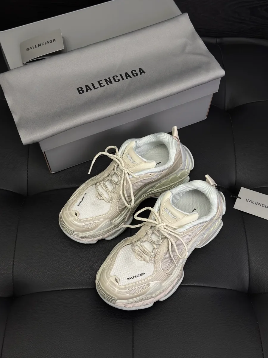 Светло-бежевые кроссовки Balenciaga рядом с коробкой и пыльником, вид сверху под углом