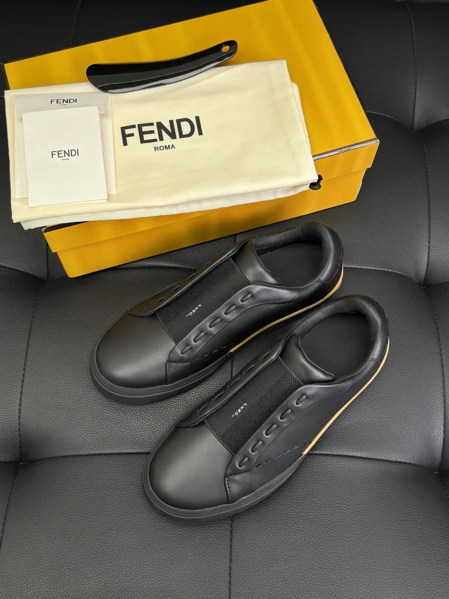 Чёрные кожаные слипоны Fendi City рядом с фирменной жёлтой коробкой, пыльником и рожком для обуви