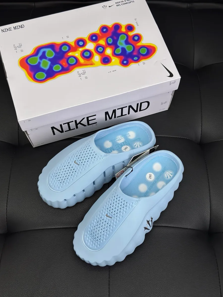 Голубые сабо рядом с фирменной коробкой Nike Mind на тёмном фоне, вид сверху