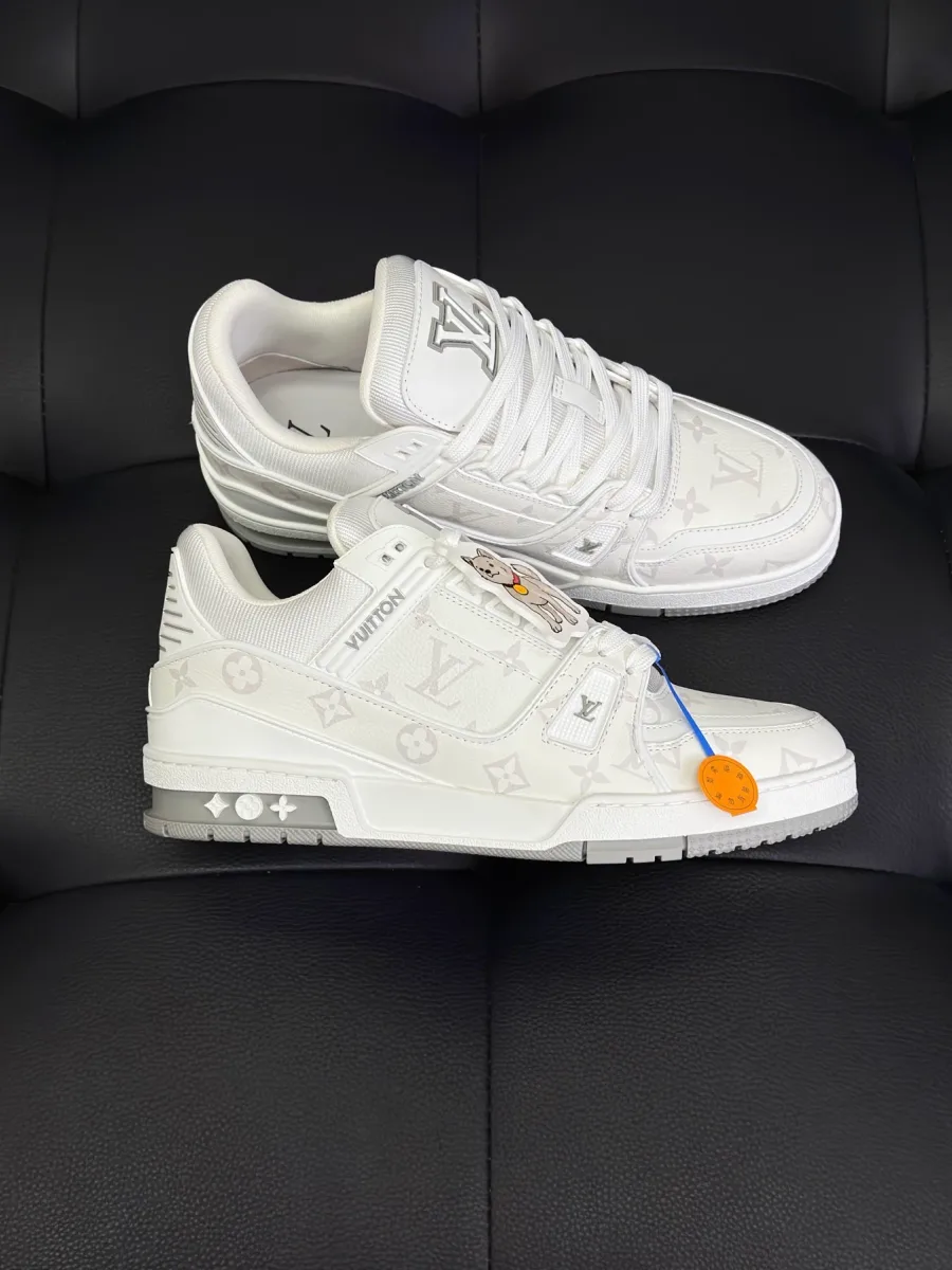 Белые кеды LV Trainer на темном фоне, вид сбоку на подошву с цветками Monogram