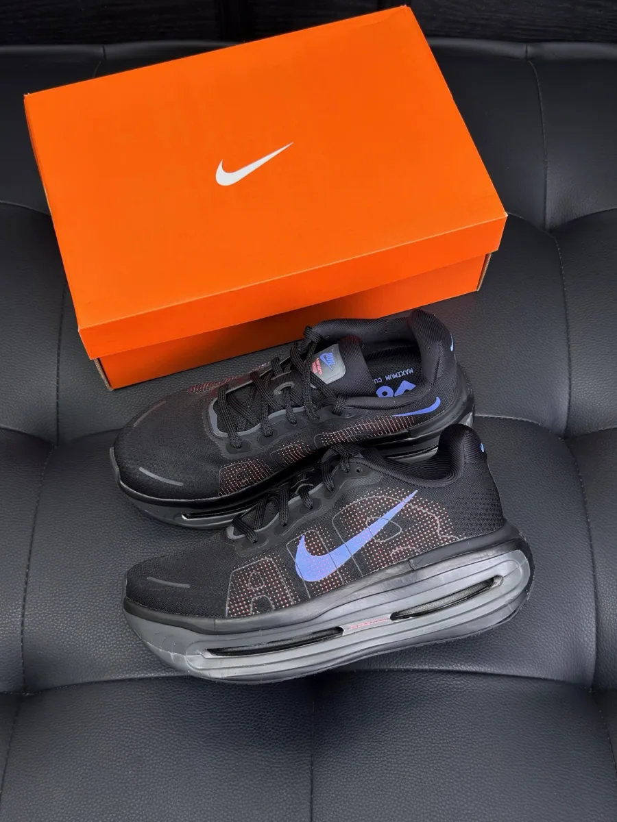 Чёрные кроссовки с массивной подошвой рядом с оранжевой фирменной коробкой Nike.