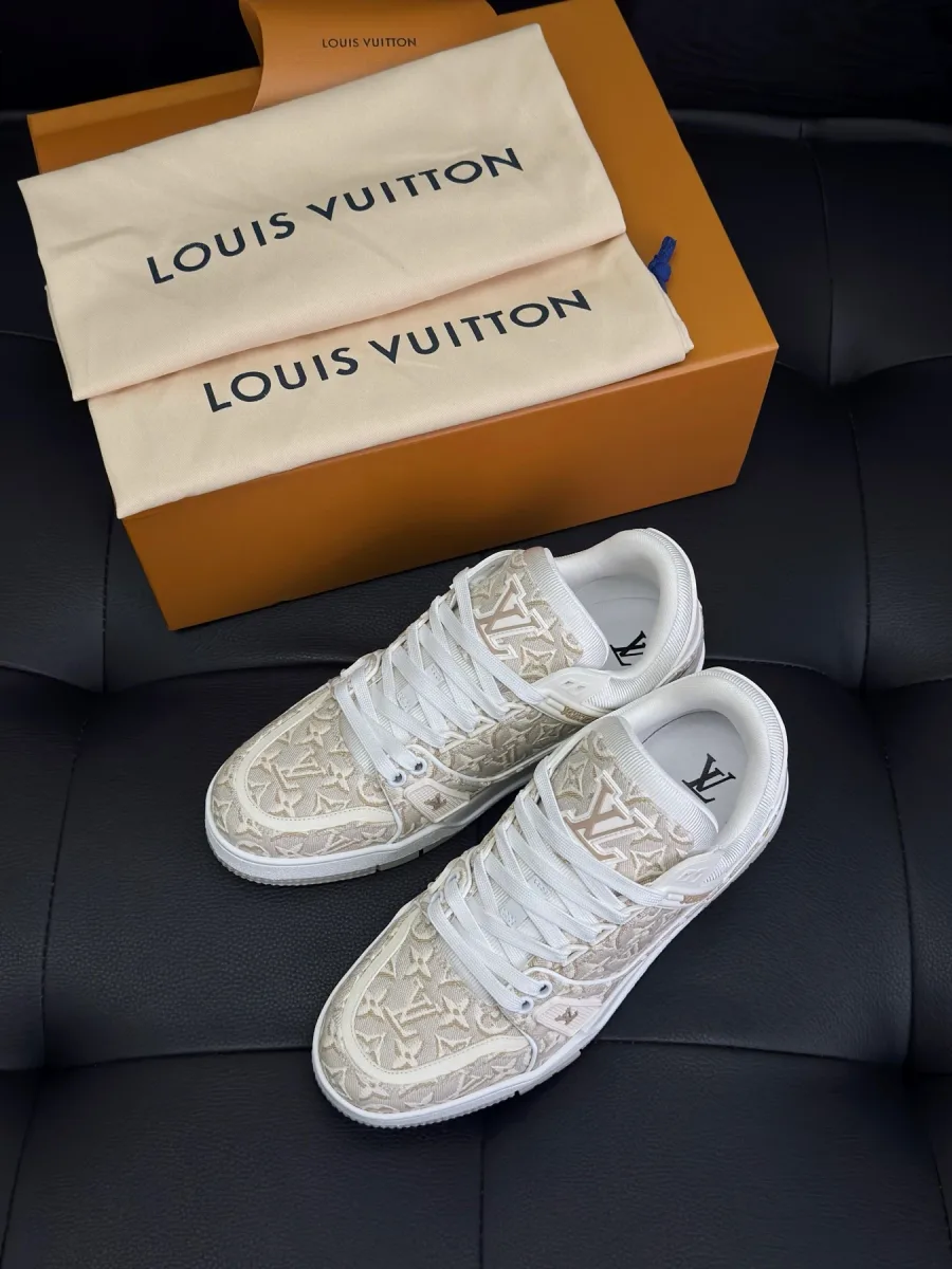 Бежево-белые кроссовки LV Trainer с жаккардовым узором рядом с фирменной коробкой и пыльниками