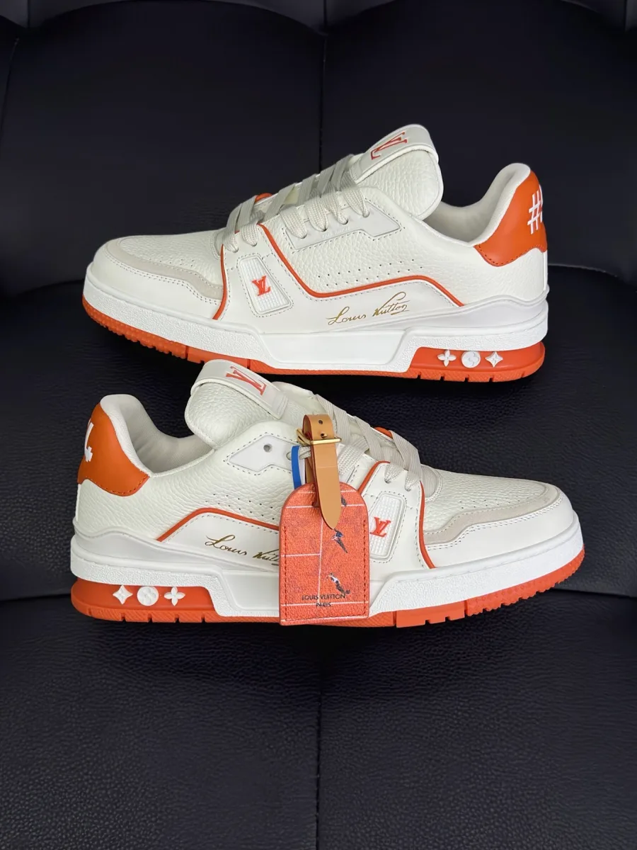 Пара кроссовок LV Trainer в бело-оранжевой расцветке, вид сбоку на кожаный верх