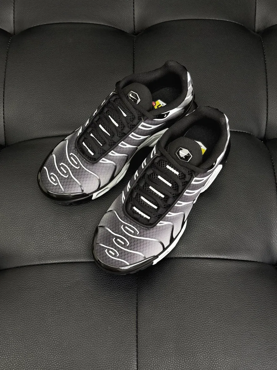 Пара чёрно-серых кроссовок Air Max Plus, ракурс сверху на чёрном фоне