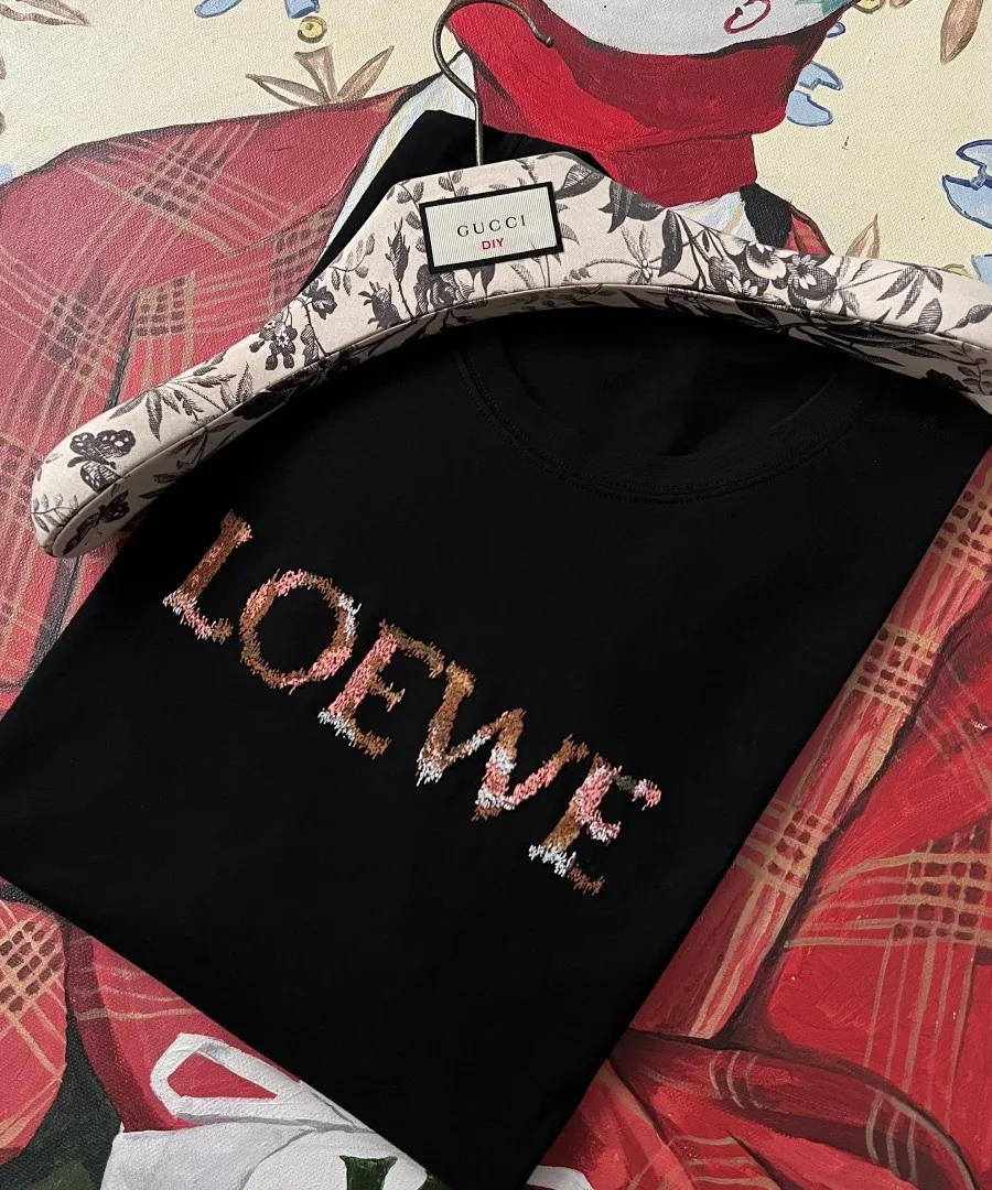 Сложенная чёрная футболка Loewe с вышитым логотипом на вешалке