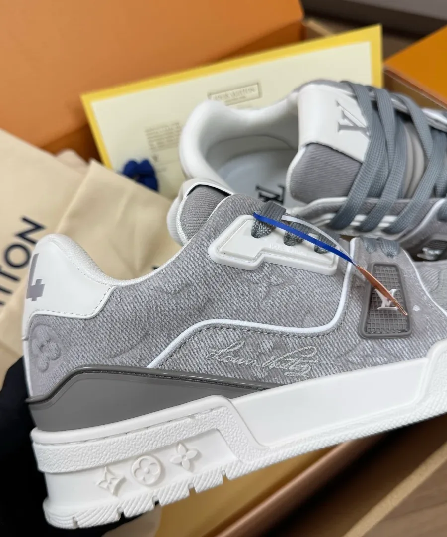 Боковая сторона серого кроссовка LV Trainer с тиснением и фирменной строчкой