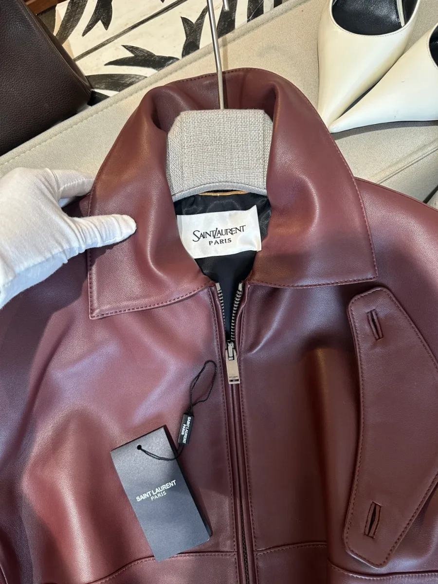 Отложной воротник бордовой кожаной куртки с биркой Saint Laurent и хлястиком