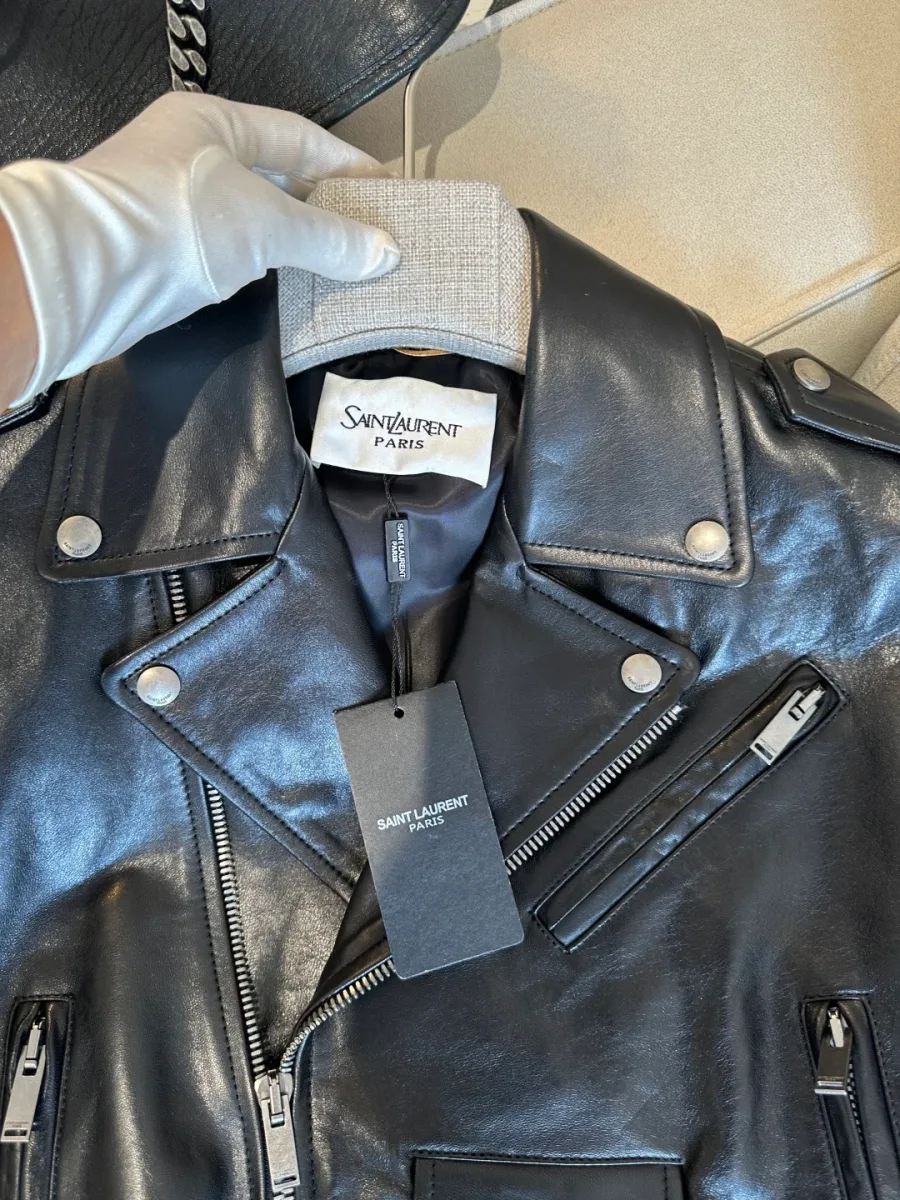 Воротник чёрной кожаной куртки крупным планом с фирменной биркой Saint Laurent Paris
