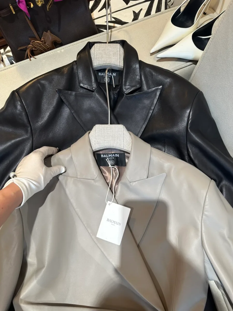 Воротник с лацканами и бирка Balmain на серо-бежевой кожаной куртке, крупный план