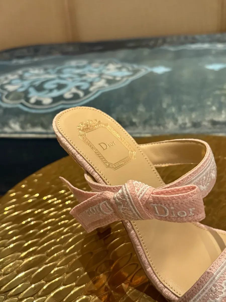 Крупный план вышитого ремешка с бантом и логотипом Dior на босоножке