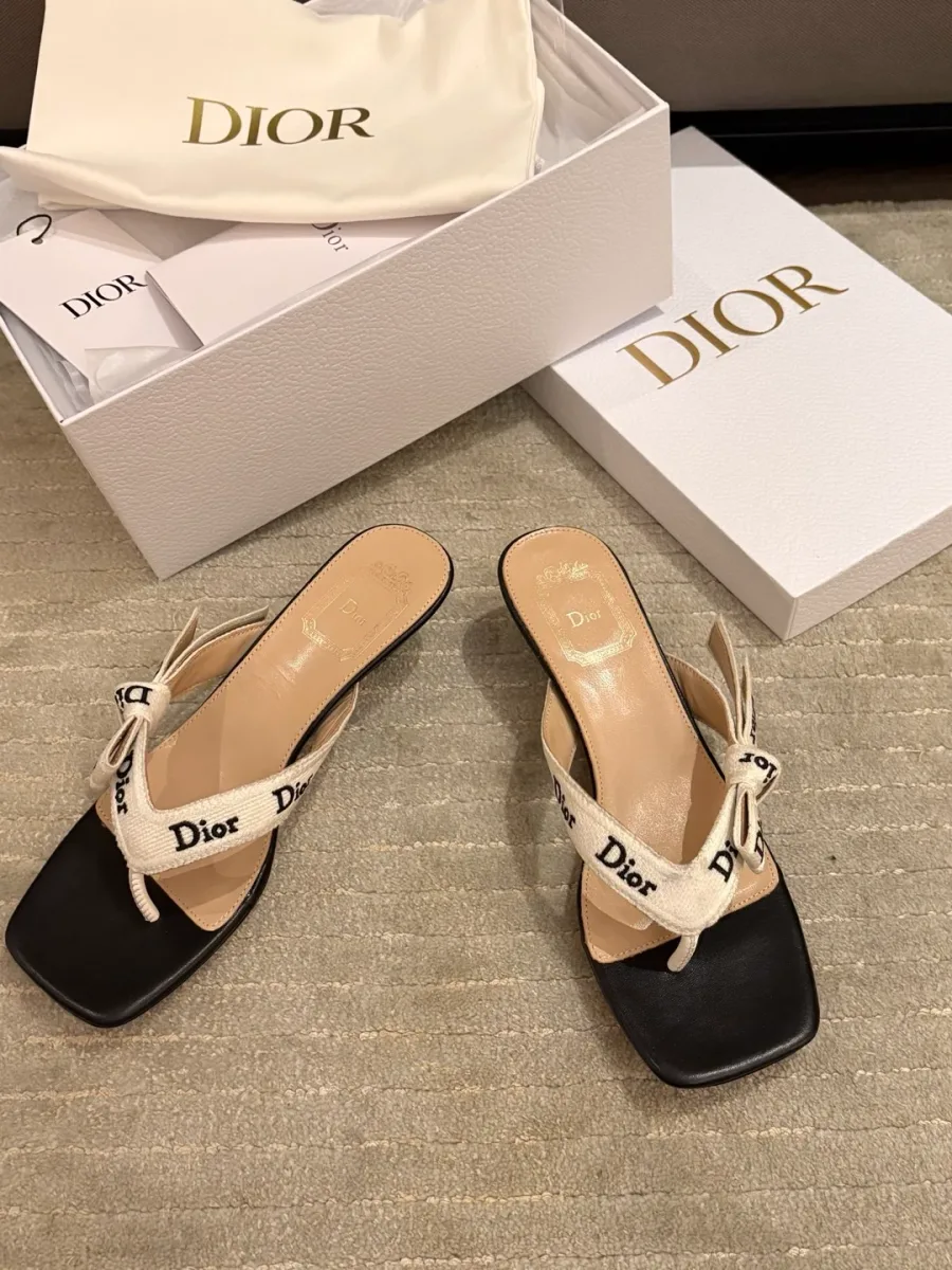 Бело-чёрные шлёпанцы Dior через палец на каблуке рядом с фирменной коробкой и пыльником