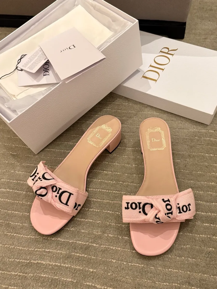 Розовые шлёпанцы Dior с вышитым бантом рядом с фирменной коробкой, вид сверху